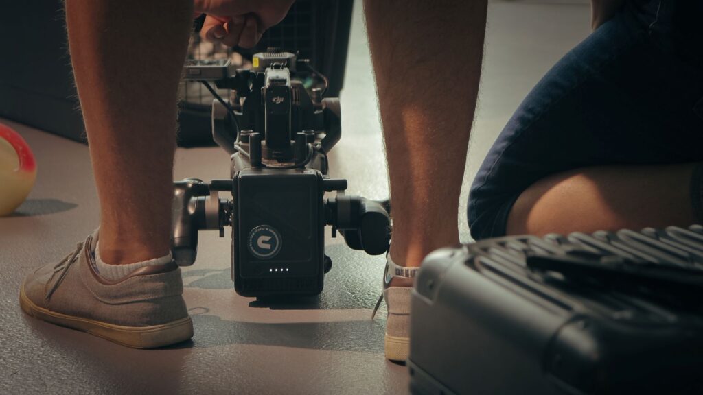 DJI Ronin 4D camera rest on floor with an Unmanned braded sticker between a videographer's feet